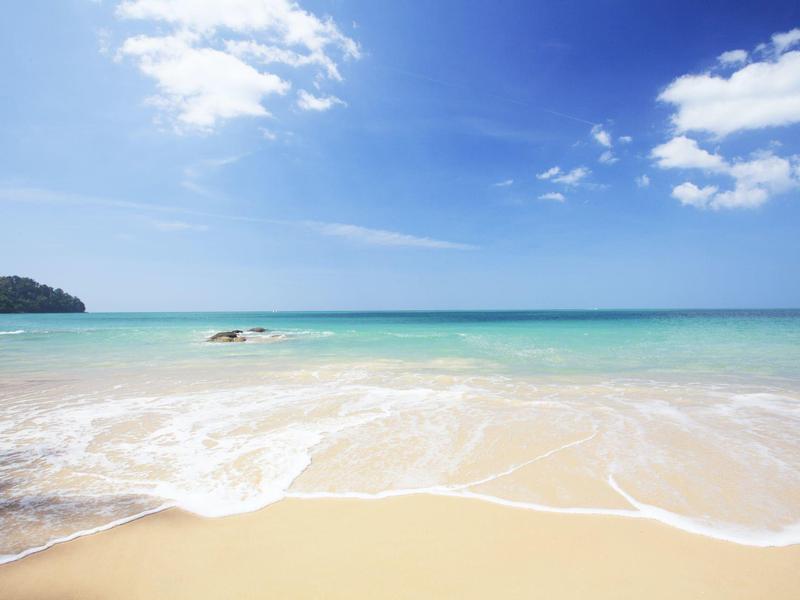 Piaszczysta plaża z łagodnymi falami i czystym niebieskim niebem