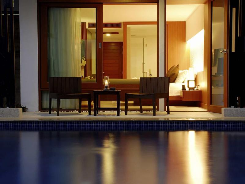 Beleuchtete Terrasse mit Sitzgruppe, Blick auf Schwimmbecken, warmes Innenraumlicht.