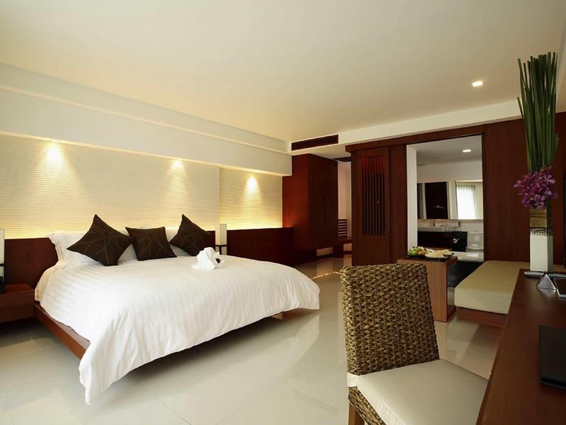 Modern eingerichtetes Hotelzimmer mit großem Bett, Schreibtisch, Stuhl und Fernseher.