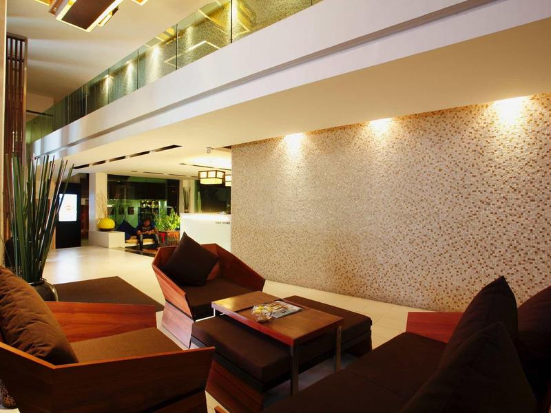 Modern eingerichteter Aufenthaltsraum mit braunen Ledersesseln, Teppichboden und indirekter Wandbeleuchtung.