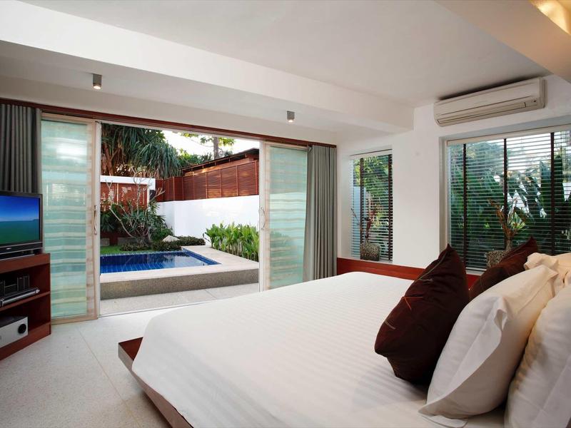 Modernes Schlafzimmer mit Doppelbett, großem Fenster, TV, Klimaanlage und Zugang zu Terrasse mit Pool.