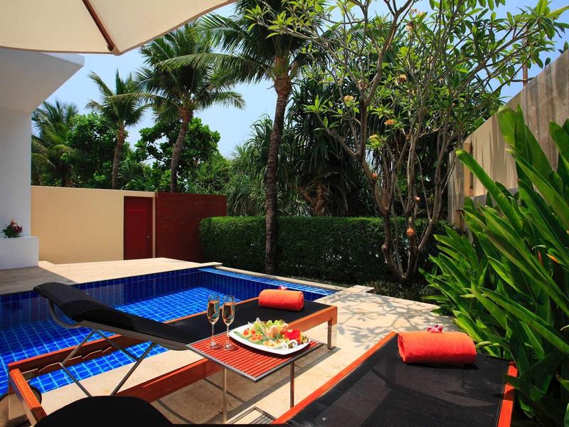 Kleiner blauer Pool mit Liegestühlen, roten Handtüchern und üppigem Grün im Hintergrund.