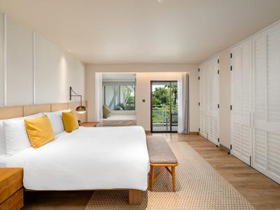 Lichte hotelkamer met twee bedden, houten meubels en uitzicht op terras en tuin.