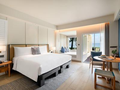 Modern hotelkamer met groot bed, zithoek en balkon met zeezicht