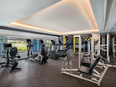 Gimnasio moderno con varios equipos de entrenamiento y grandes ventanas con vista.