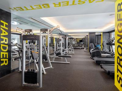 Gimnasio moderno con muchas máquinas de ejercicio y palabras motivadoras amarillas en las paredes.