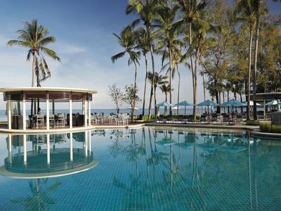 Piscina grande con palmeras y pabellón junto al mar bajo cielo despejado