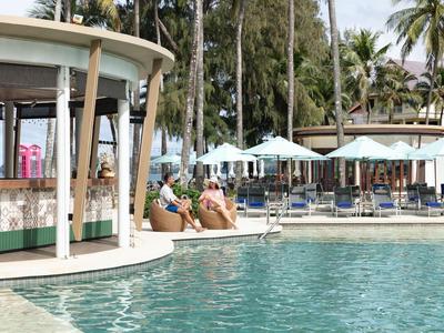 Bar en la piscina con huéspedes, tumbonas y palmeras en un resort tropical.