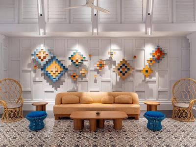 Sala moderna con sofá marrón, dos sillas de mimbre y decoraciones de pared coloridas.