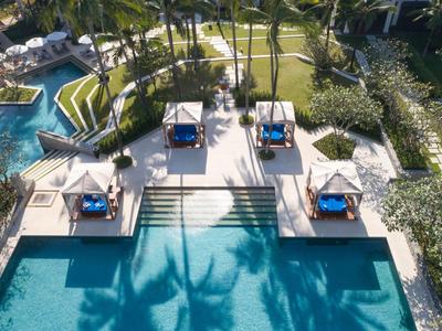 Vista aérea de una zona de piscina con tumbonas y sombrillas en un hotel tropical.