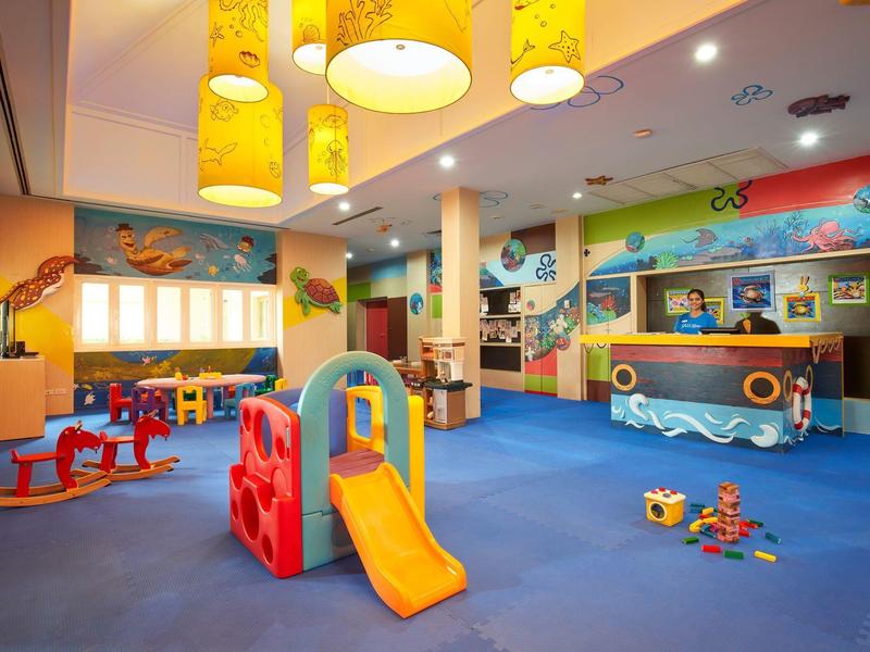 Kleurrijke binnen speelruimte met glijbaan, speelgoed en kindvriendelijk meubilair in een hotel.