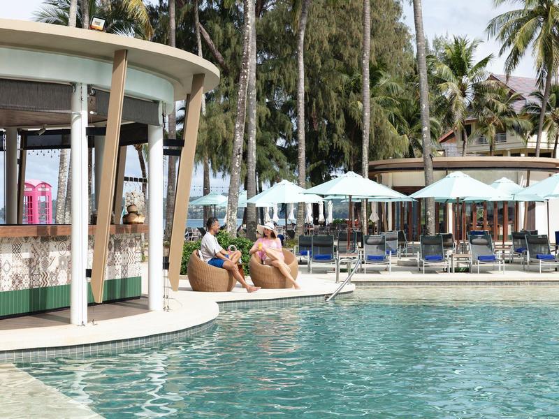 Zwembad met bar, ligstoelen en palmbomen in tropisch hotel