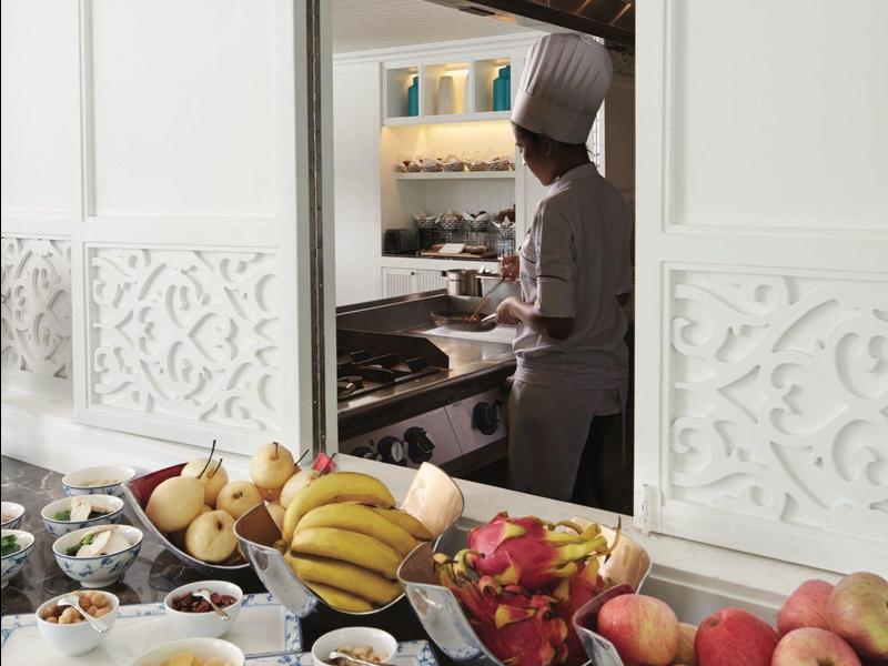 Buffet met vers fruit, gebak en jam voor keukendeur met uitzicht op kok.