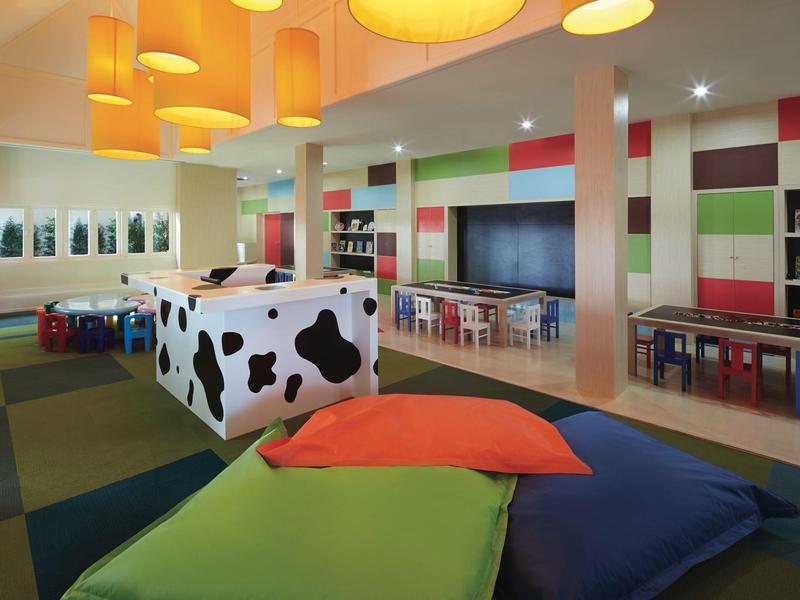 Kleurrijke, moderne speelruimte in hotel met kussens en kubussen met dierenpatroon.