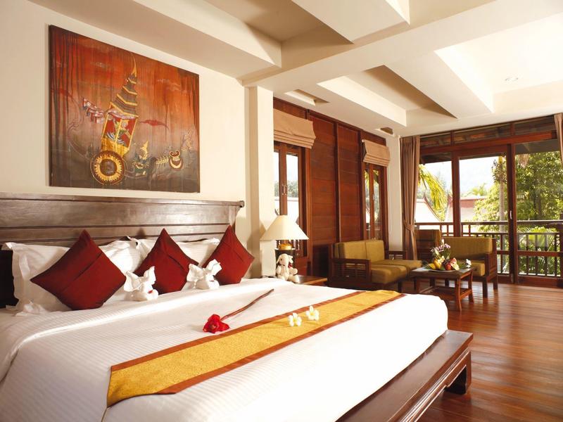 Ruime hotelkamer met tweepersoonsbed, houten vloer en balkon met uitzicht buiten.