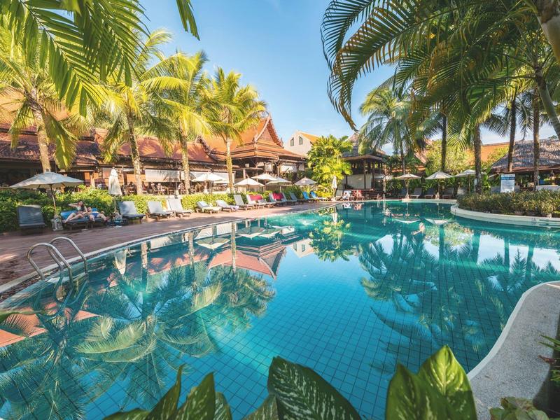 Uitnodigend zwembad met palmbomen, ligstoelen en parasols in een resort.