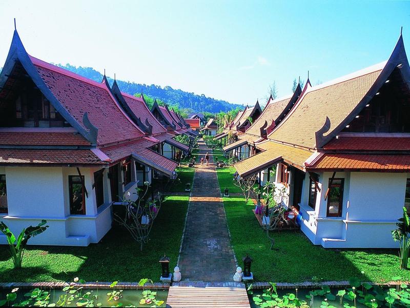 Uitzicht op traditionele Aziatische bungalows met rode daken langs een pad.
