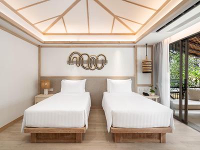 Modern hotel room with two single beds, wood decor, and balcony access with nature view.