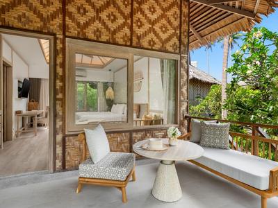 Gemütliche Außensitzgruppe mit Lounge-Stuhl und Tagesbett vor dem Hotelzimmer mit Bambusfassade.