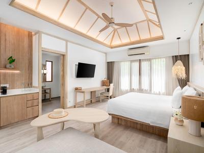 Bright hotel room with large bed, TV, desk, and modern design.