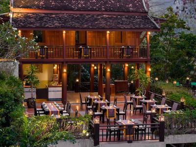 Gemütliches Restaurant mit Holzmöbeln und warmer Beleuchtung in einem tropischen Gartensetting.