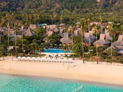 Tropisches Hotelresort mit Strohdach-Bungalows, Pool und Strand mit Liegestühlen an türkisfarbenem Meer.