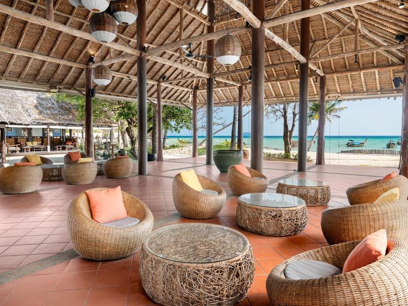 Open lounge area with wicker chairs and tropical sea view.