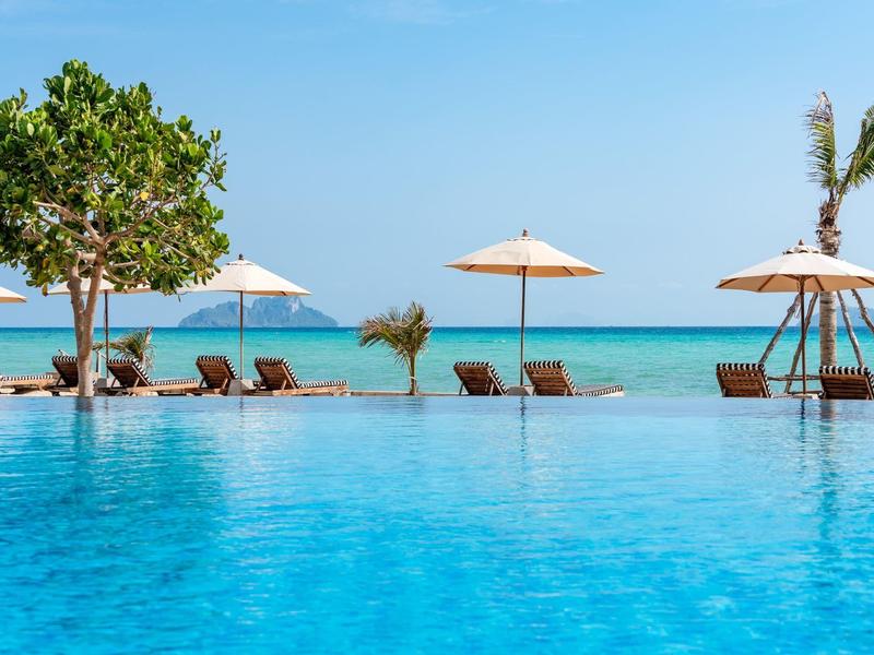 Infinity pool with loungers and umbrellas by the sea on a sunny day.