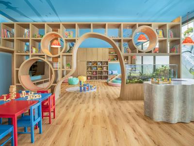 Sala giochi colorata per bambini con pavimenti in legno, tavoli, sedie e scaffali.