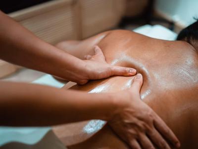 Un massaggio con le mani che premono sulla schiena di una persona.