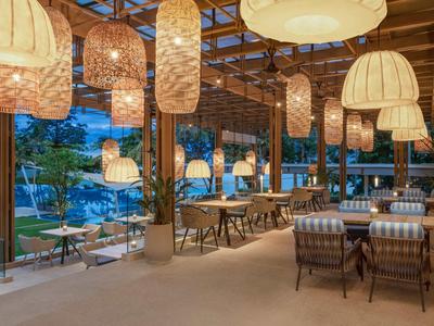 Area pranzo aperta con lampade sospese e vista su piscina all'aperto.