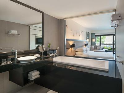 Bagno moderno con vasca nera e grande specchio in una camera d'hotel.