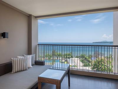 Balcone con zona lounge accogliente, vista sul mare e cielo sereno.