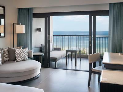 Camera d'hotel moderna con divano, scrivania e balcone con vista sul mare.