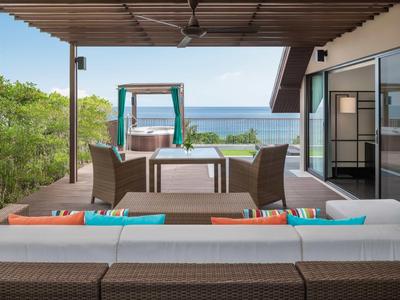 Area esterna moderna con mobili e vista mare sotto una pergola.