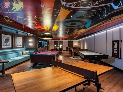 Sala giochi moderna con tavolo da biliardo, air hockey, ping pong e zona salotto accogliente.