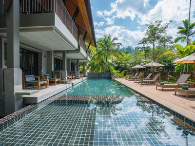 Modern outdoor pool with sun loungers and umbrellas in a tropical hotel setting