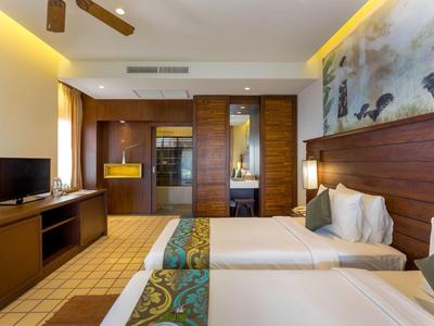 Modern hotel room with two single beds, TV, and ambient lighting.