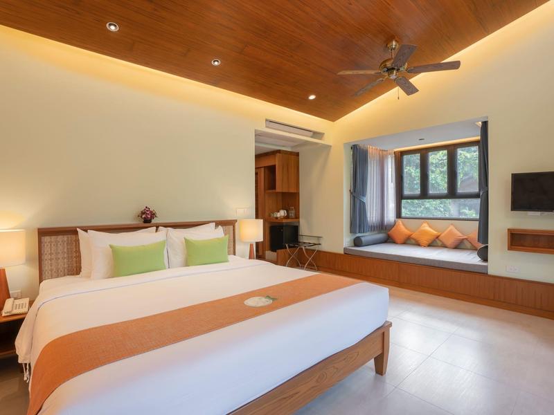 Modern bedroom with large bed, wooden ceiling, window seat, and wall-mounted TV.