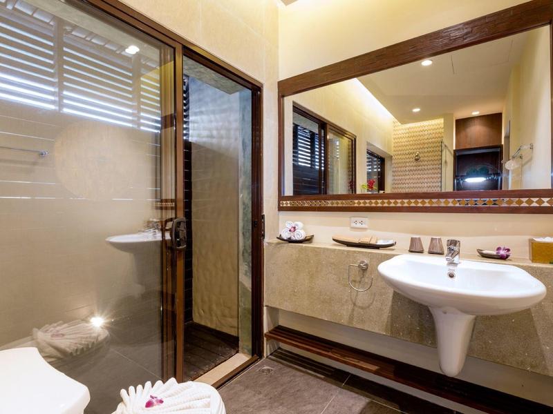 Modern bathroom mirror with sink and shower cabin in a warmly lit room.