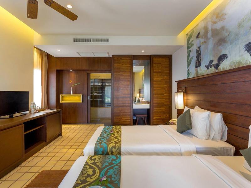 Modern hotel room with two single beds, TV, and ambient lighting.