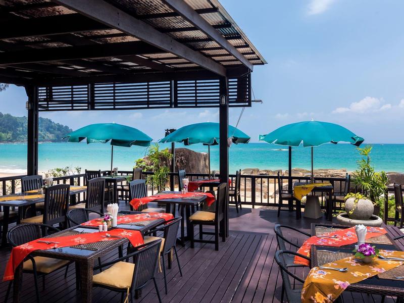 Open restaurant with wooden terrace overlooking the beach and ocean.