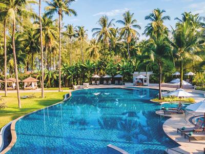 Velký bazén s palmami a lehátky v tropickém resortu.