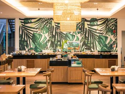 Moderně zařízená restaurace s tropickou nástěnnou dekorací a dřevěným nábytkem.