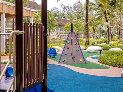 Kinderspielplatz mit Klettergerät, blauer Gummiboden und grüner Umgebung in einer Wohnanlage
