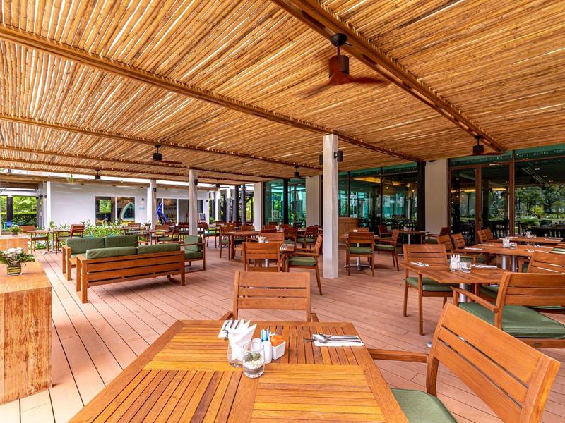 Überdachte Außenterrasse mit Holztischen und Stühlen in einem Hotelrestaurant.