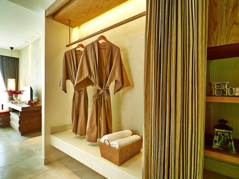 Offener Kleiderschrank mit zwei braunen Bademänteln, Korb mit Handtüchern, daneben Regal und Vorhang.