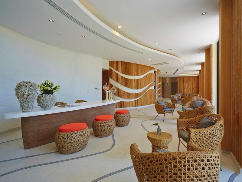 Moderner Warteraum mit geschwungenem Thekenbereich, Rattanmöbeln und warmem Holzakzent.