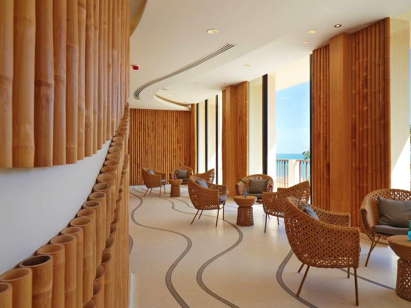 Lounge mit Rundstühlen und Bambusdekoration, helle Räume mit großen Fenstern und Meerblick.