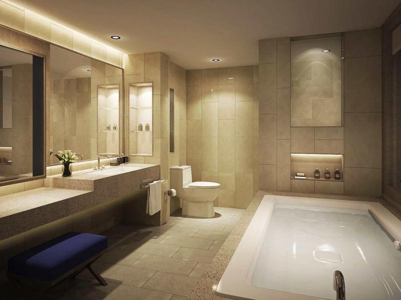 Moderne badkamer met bad, toilet, dubbele wastafels en warm licht.